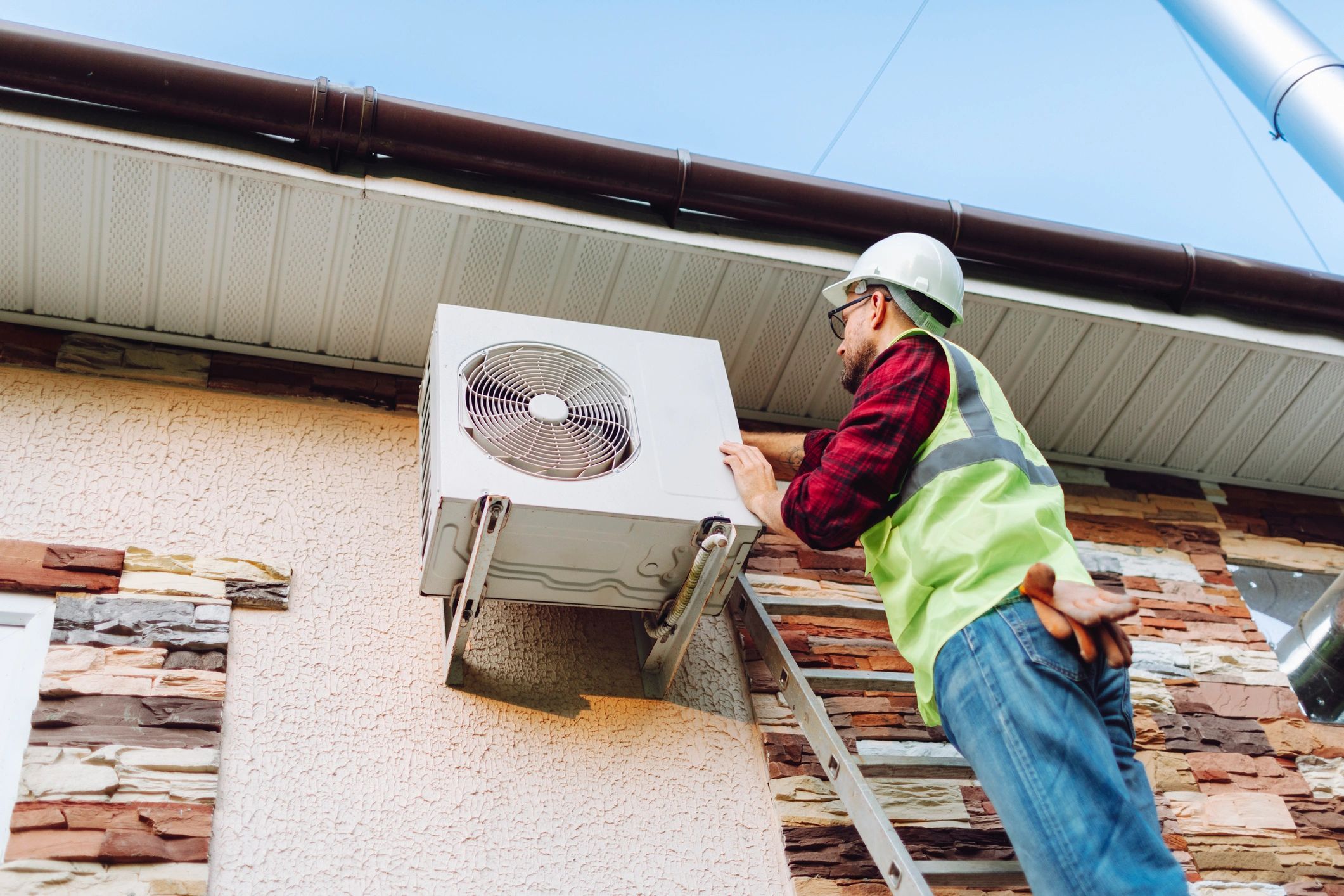 A man fixing an Air conditioning unit outside of a residential unit
